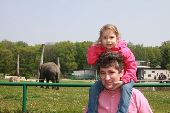 Weronika na ramionach taty w zoo – uśmiech i ciekawość.